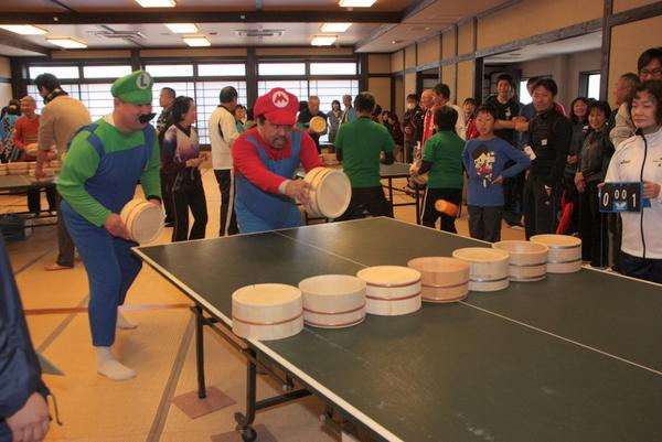 スーパーマリオの赤と緑の衣装を着た2名の方が桶を持って構えている写真